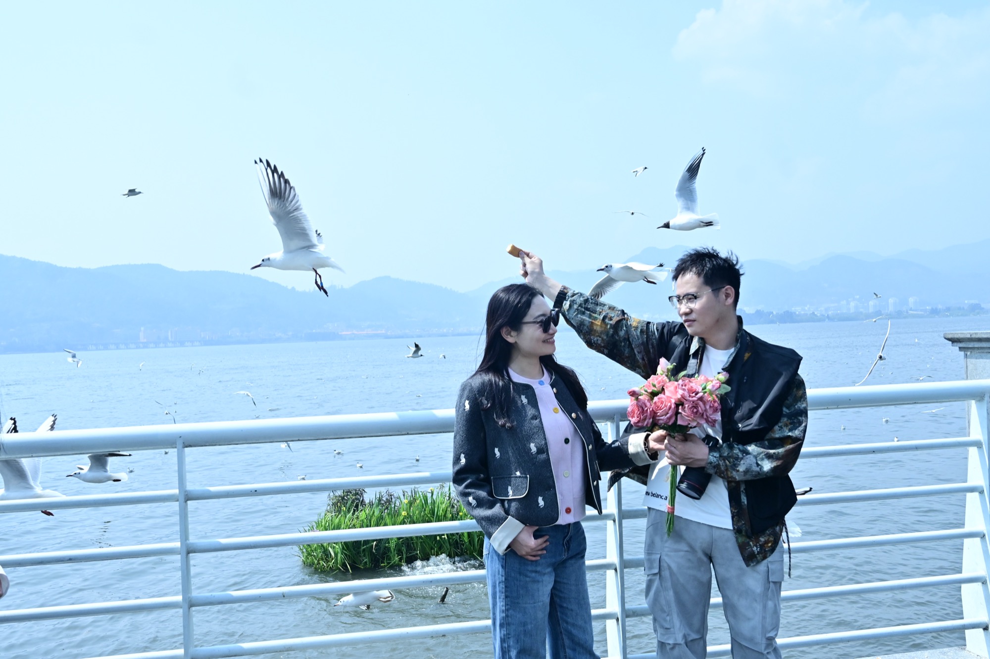滇池大坝合影：在领举着面包引海鸥，晶晶在他身旁笑