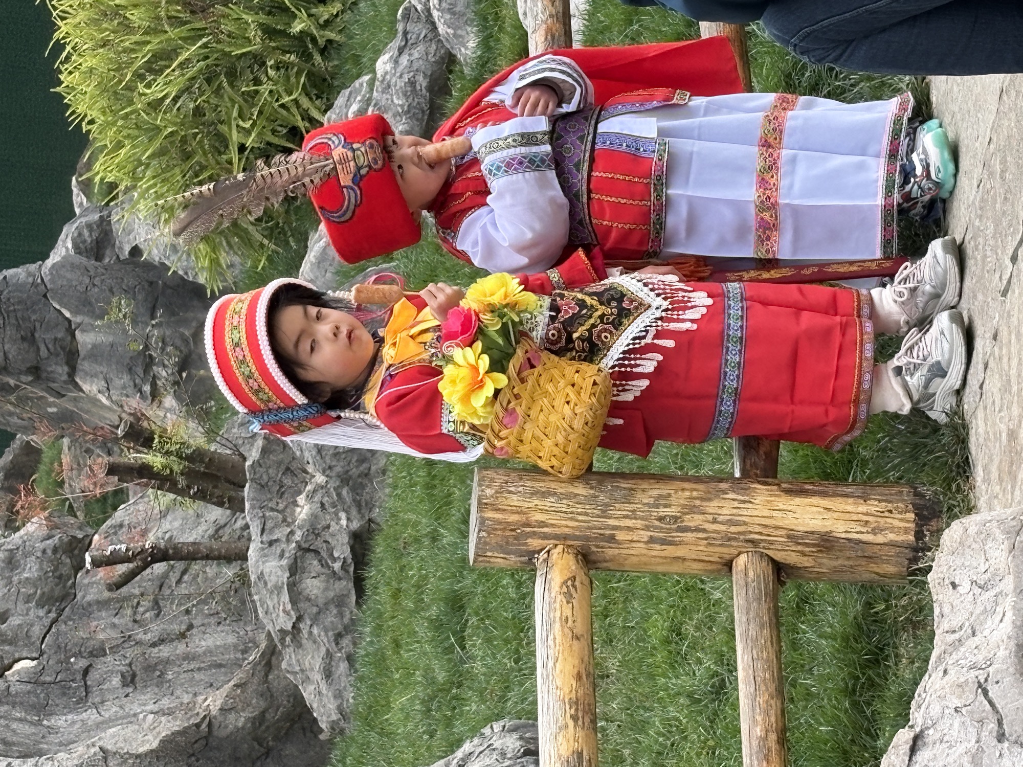 两个穿彝族传统服饰的小朋友在石林里吃小吃