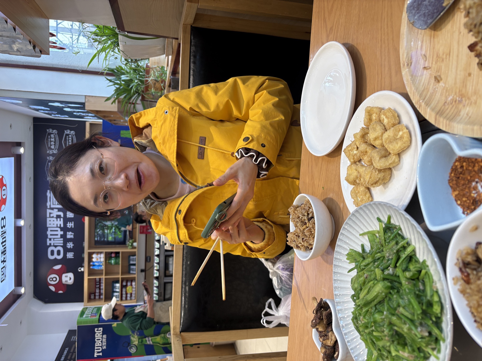 野生菌餐厅里，晶晶穿黄色外套准备开动，桌上摆着炸乳扇和青菜