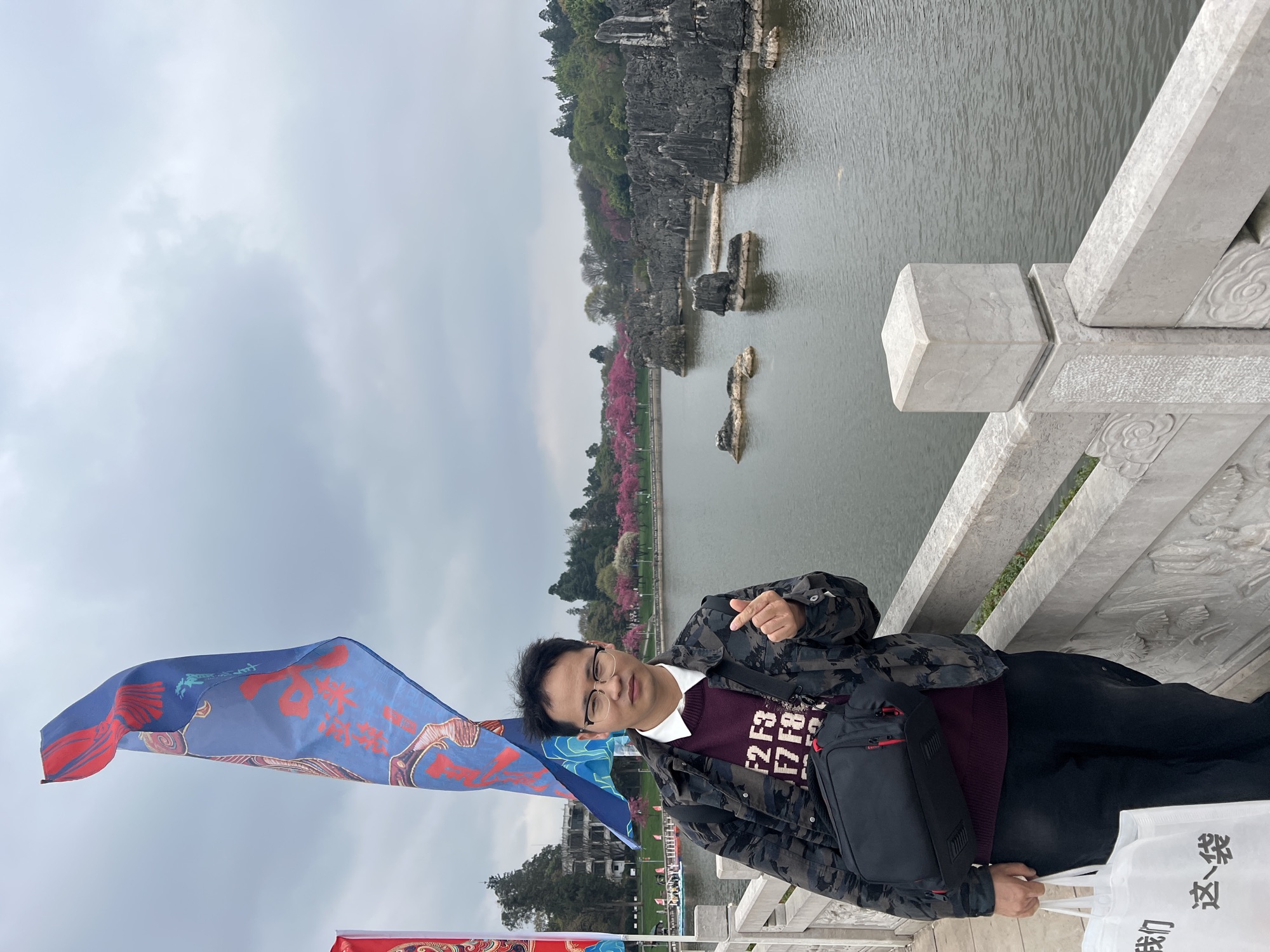 在领站在石林湖边的石桥上，蓝色旗帜飘着